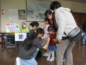 カエルバッチを高校生ボランティアが子どもにつけている様子